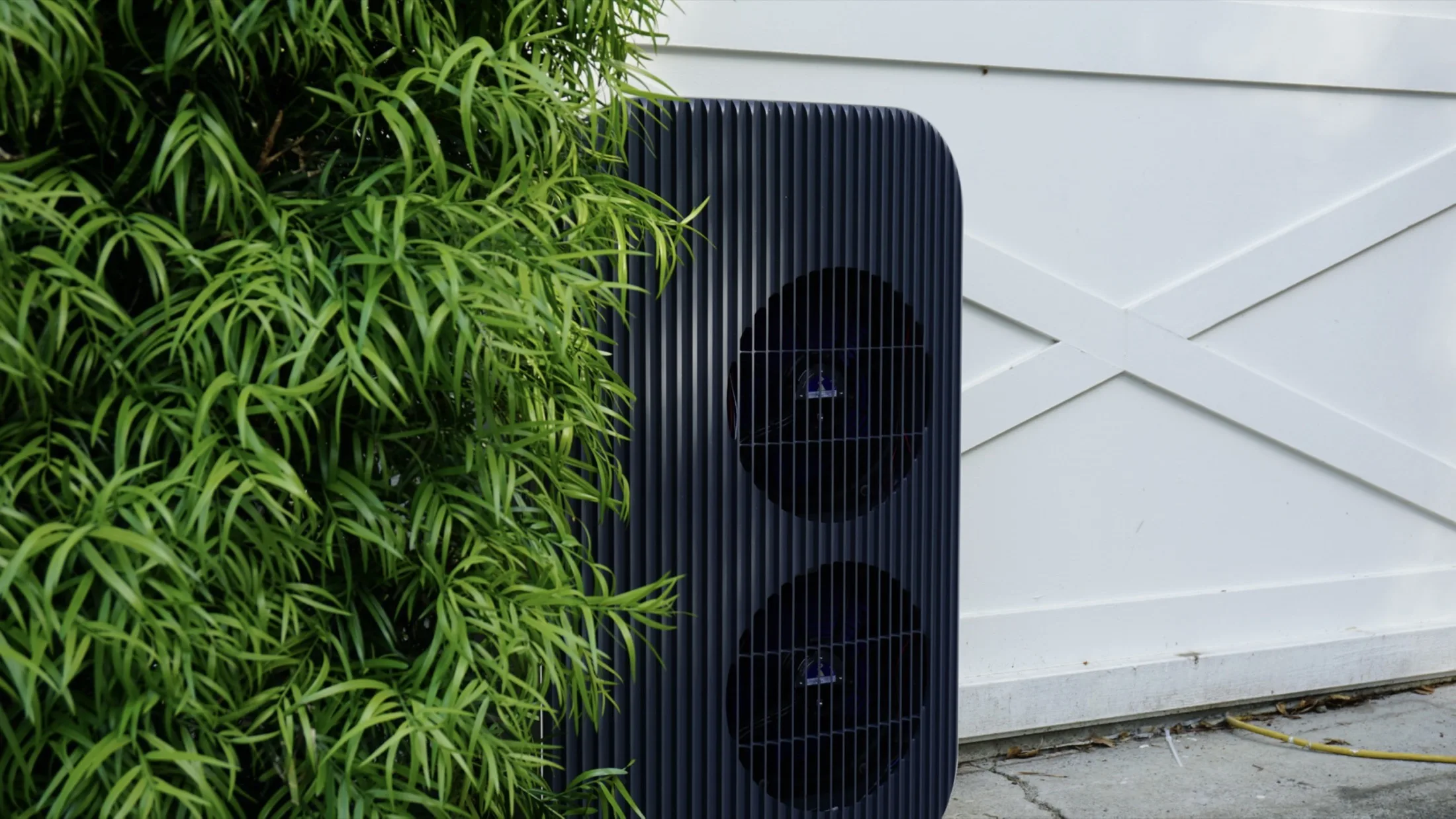 Airform outdoor unit in charcoal beside a garden hedge